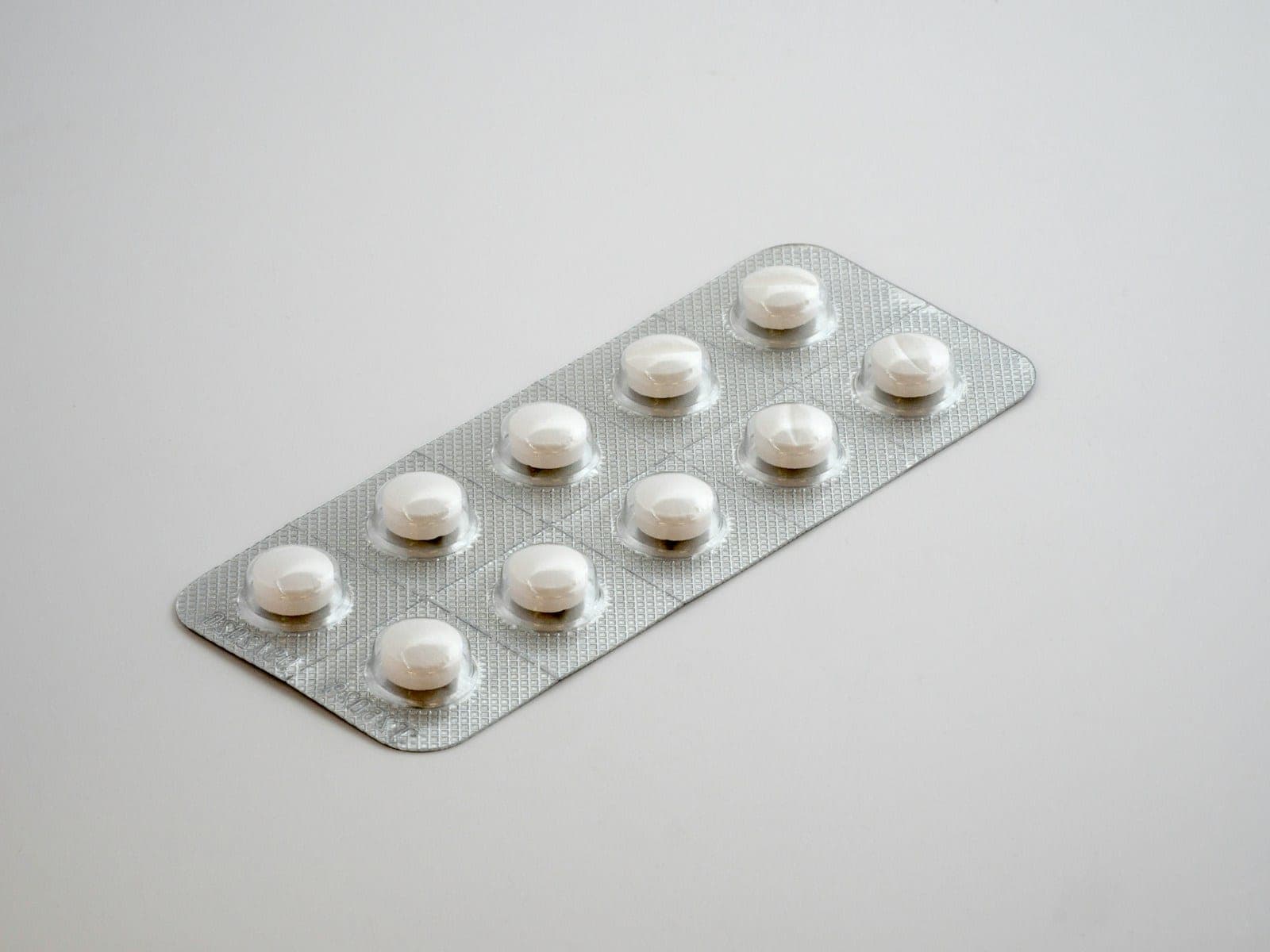 A blister pack of white tablets on a plain white surface