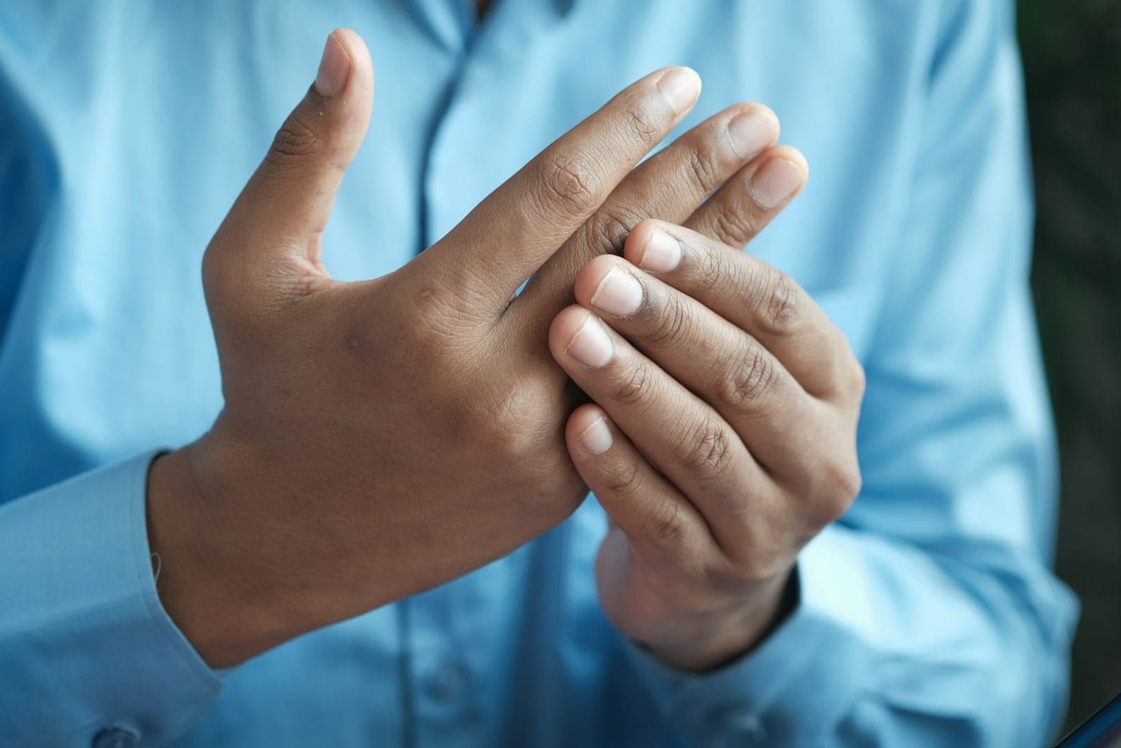 A person holding one hand in the other, fingers interlaced