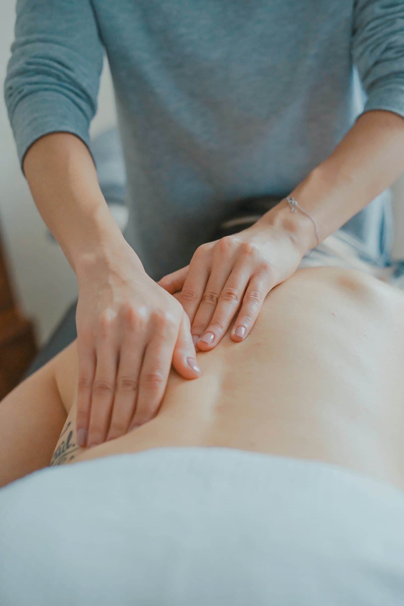 A therapist's hands assessing a patient's lower back