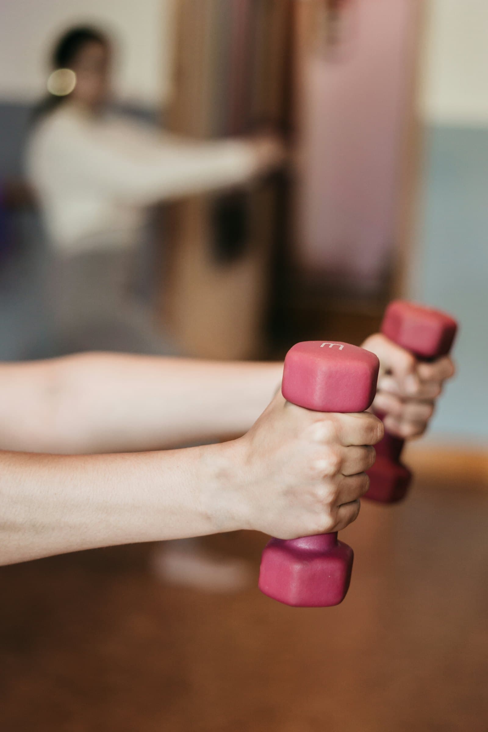 Hands holding light dumbbells during a strengthening exercise