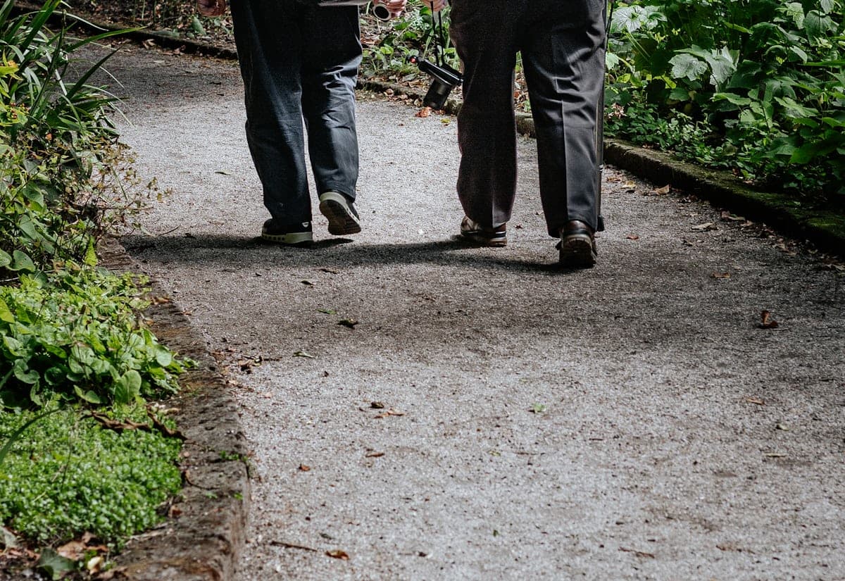 Two older adults walking together along a garden path